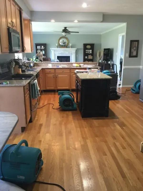 Air movers drying a kitchen and its hardwood floor after a leak