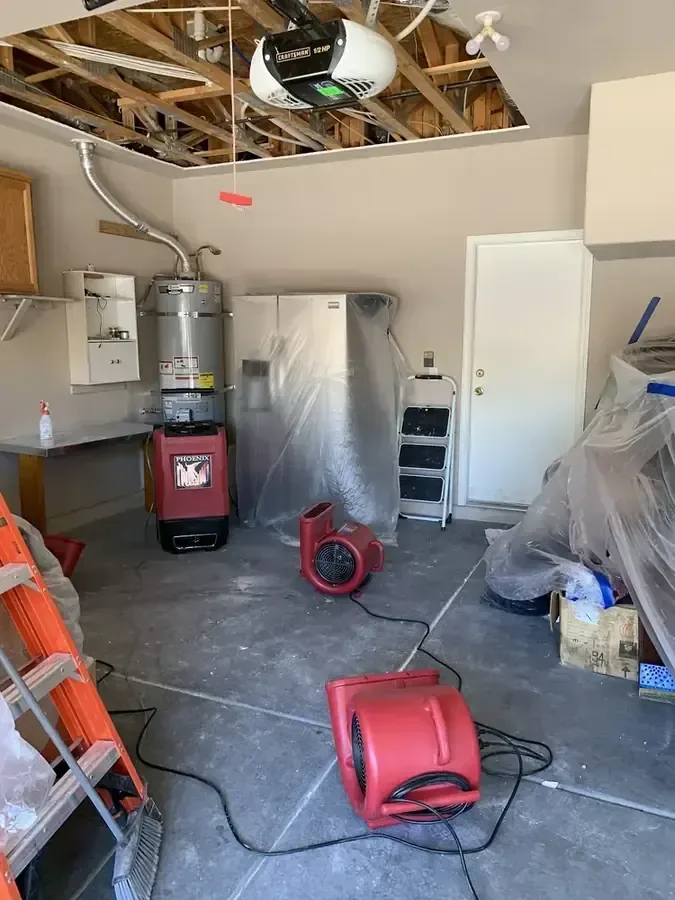 Drying equipment in a garage with the ceiling opened after a water heater leak