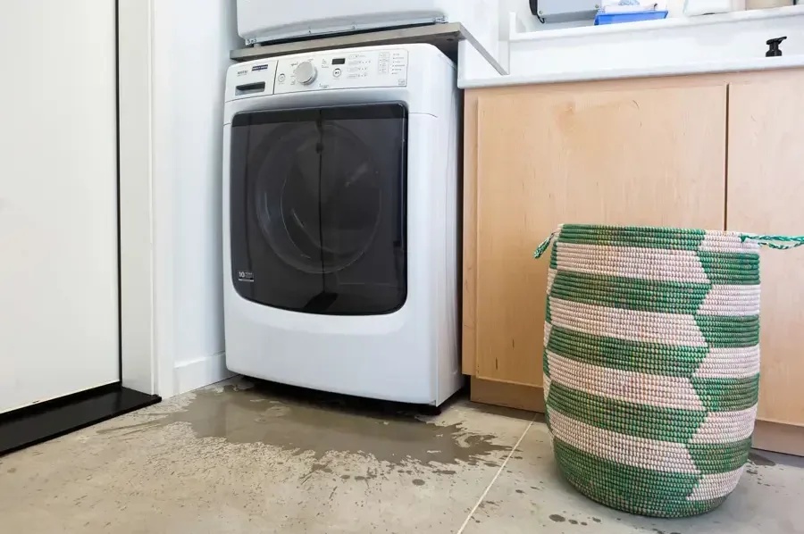 Water pooled on a floor in front of a washing machine